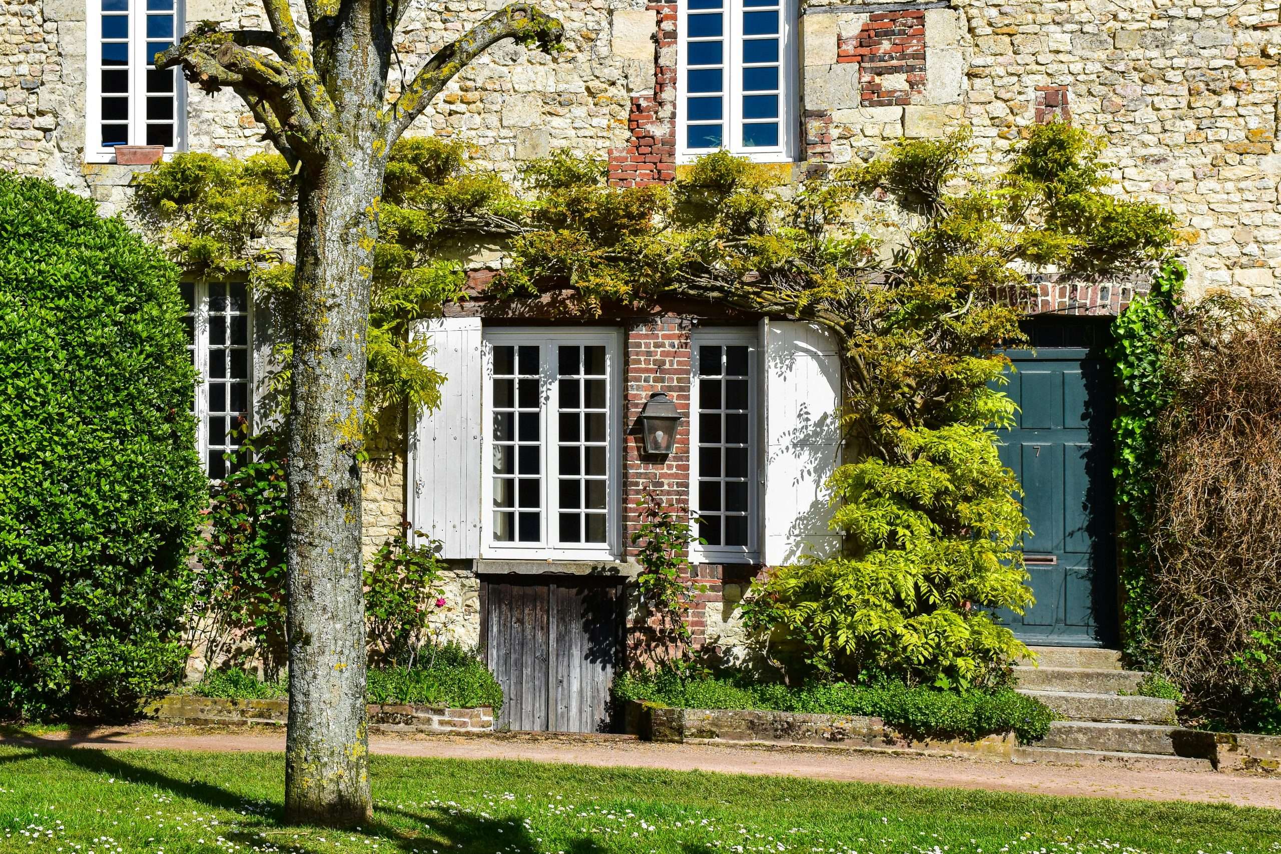 Charming stone facade with lush greenery in French countryside setting.