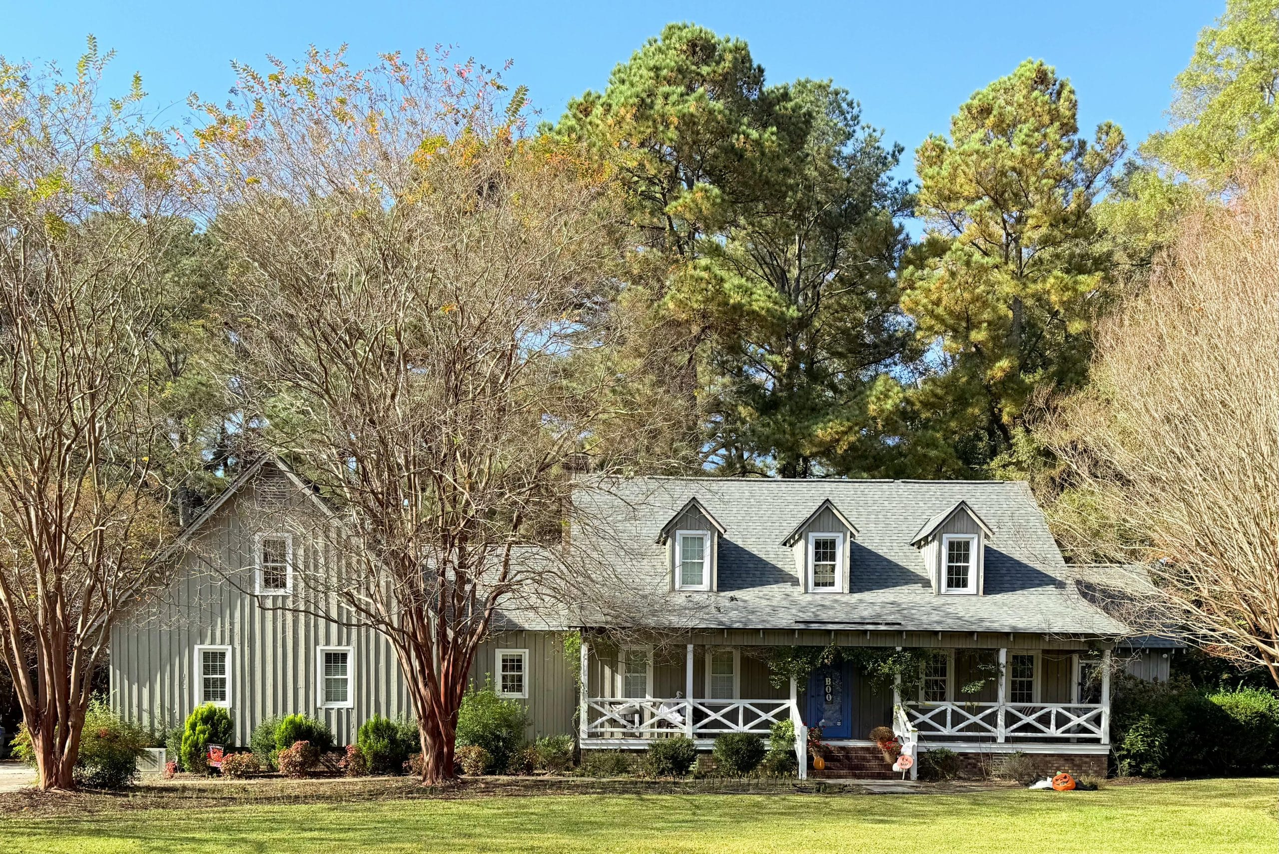 A picturesque ranch-style house surrounded by autumn trees and greenery.