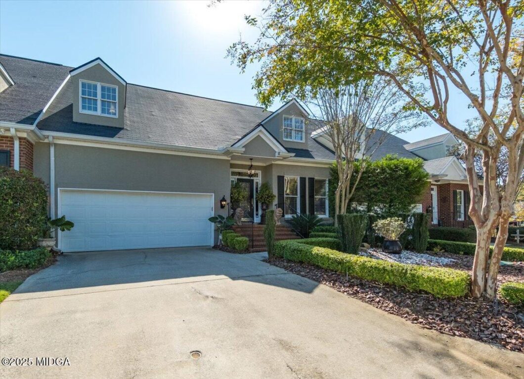 Front view of a two-car garage suburban home with a manicured front yard and brick steps leading to the entryway.