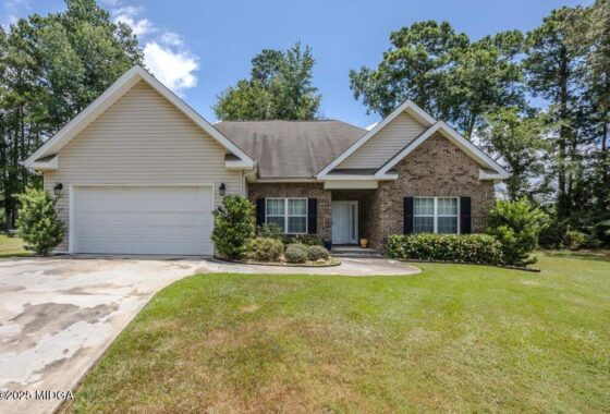 Front view of a single-story suburban house with a two-car garage, brick and siding exterior, and a green lawn.