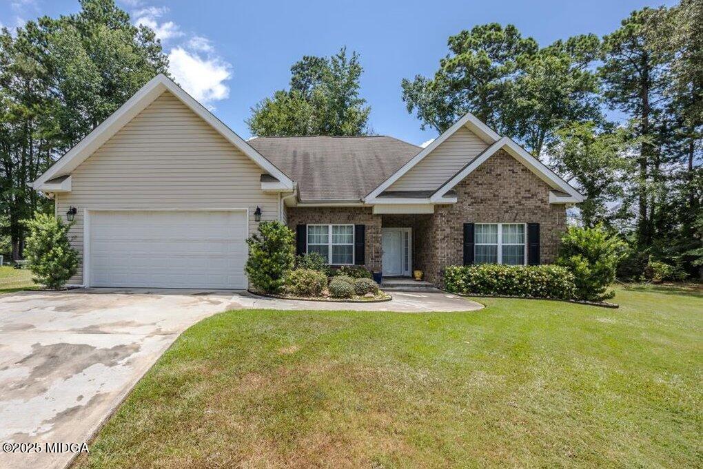 Front view of a single-story suburban house with a two-car garage, brick and siding exterior, and a green lawn.