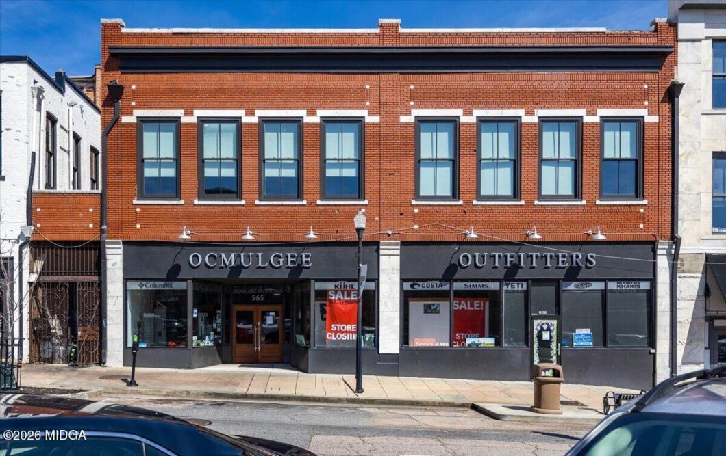Brick storefront for OCMULGEE OUTFITTERS on a two-story brick building with large display windows and sale signs in the windows.