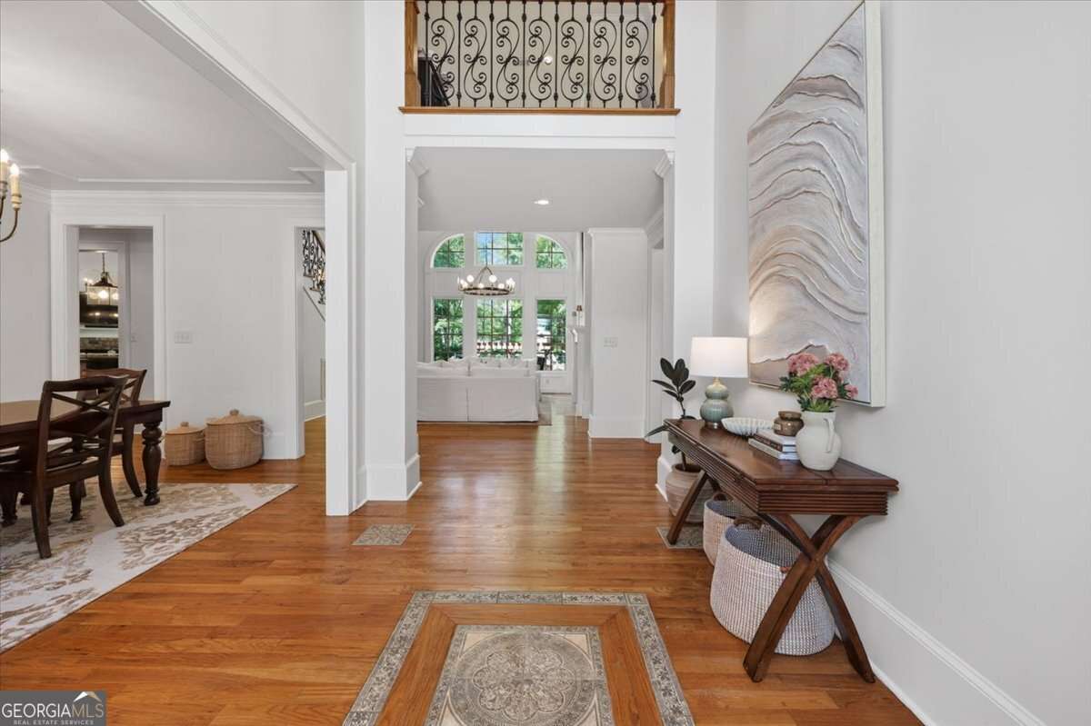 Bright foyer with warm hardwood floors, a wooden console table on the right, and a large abstract wall piece above.
