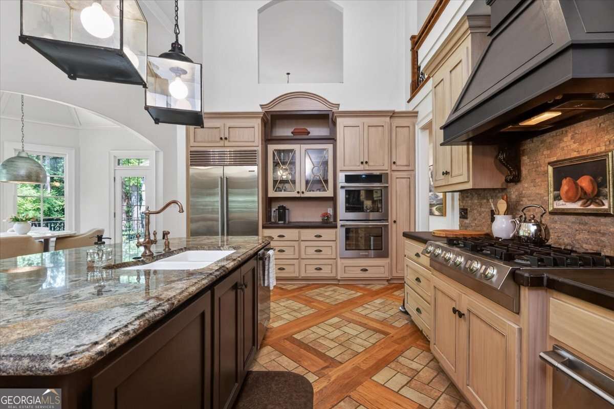 Spacious kitchen with a granite island, stainless steel fridge, and built-in ovens.