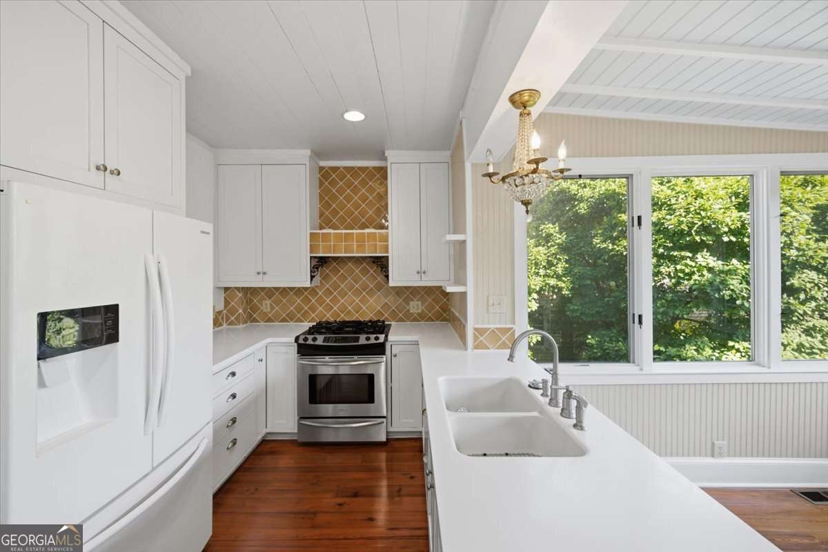 Image of kitchen with clean countertops, hardwood floors, and large windows.