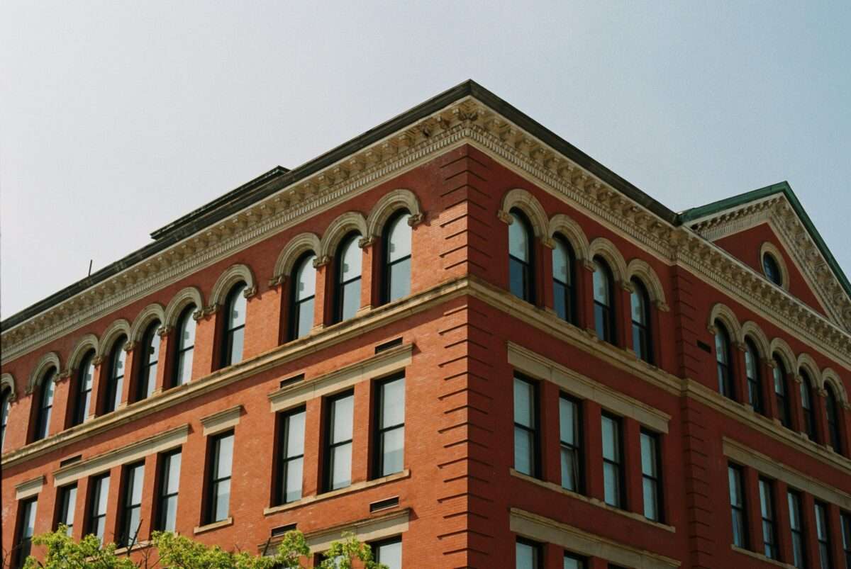 Red brick corner building with arched windows and decorative cornice against a clear blue sky