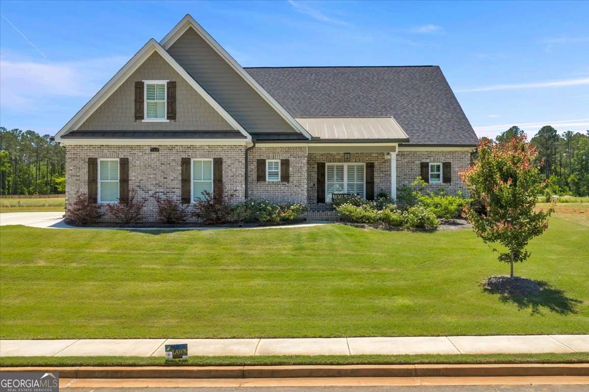 Brick ranch-style house with steep gabled roof, front porch, and brown shutters, surrounded by a green lawn and landscaping.