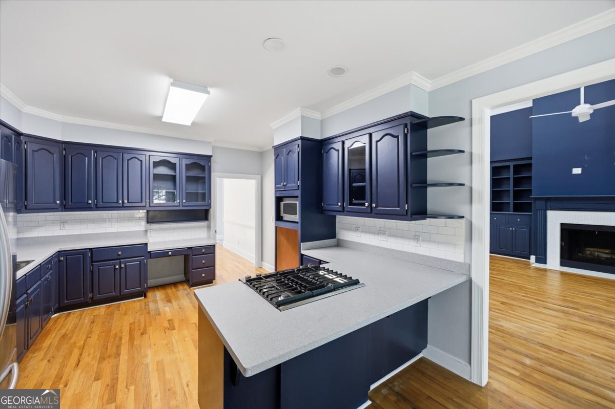Spacious kitchen at 216 Hunters Hill Court featuring custom dark cabinetry, center island cooktop, hardwood flooring, and open flow into the adjoining living area with fireplace.