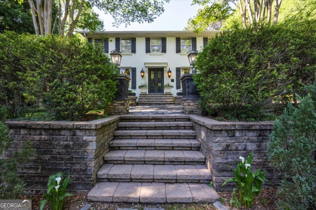 Front exterior view of 4717 Brae Burn Lane in Saint Andrews featuring elegant white brick architecture, grand stone entry staircase, mature landscaping, and private luxury estate setting in North Macon.