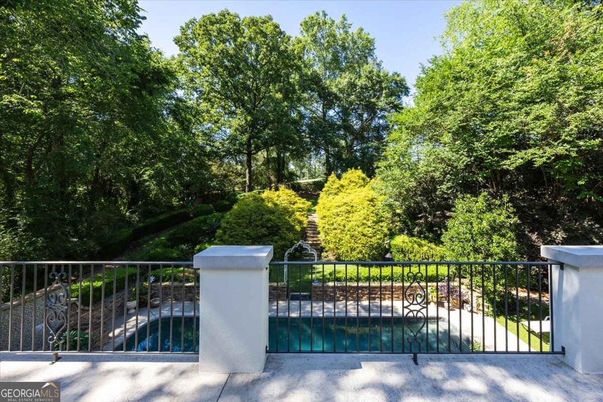 Elevated terrace view at 4717 Brae Burn Lane overlooking the private inground pool, manicured landscaping, and peaceful wooded surroundings in the Saint Andrews luxury community.