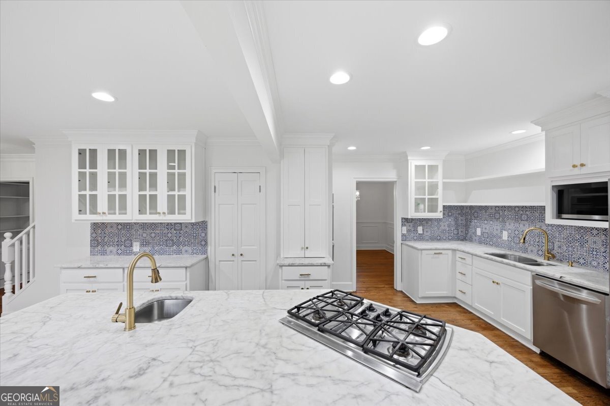 Luxury renovated kitchen at 3561 Overlook Avenue in Midtown Macon featuring marble countertops, custom white cabinetry, designer tile backsplash, and oversized island with gas cooktop.