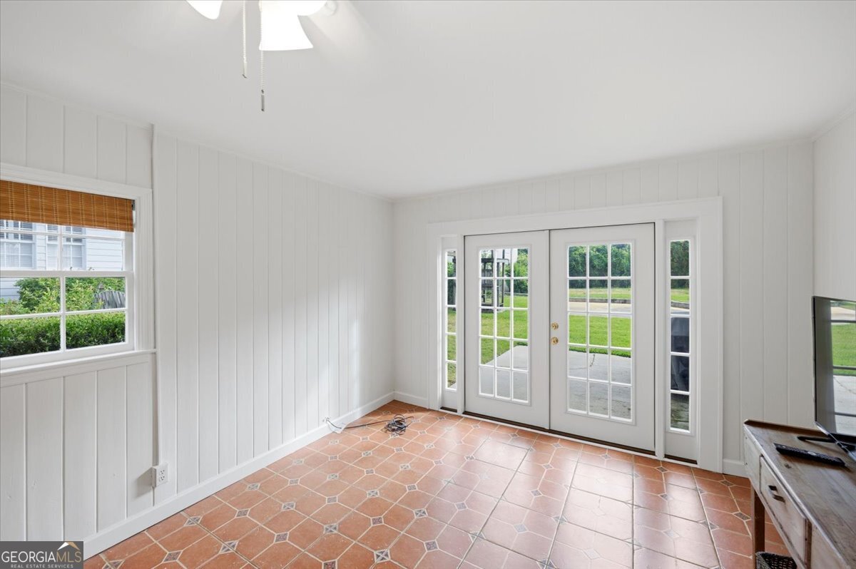 Bright sunroom and flexible living space at 3561 Overlook Avenue in Midtown Macon featuring French doors, classic tile flooring, abundant natural light, and views of the backyard patio area.