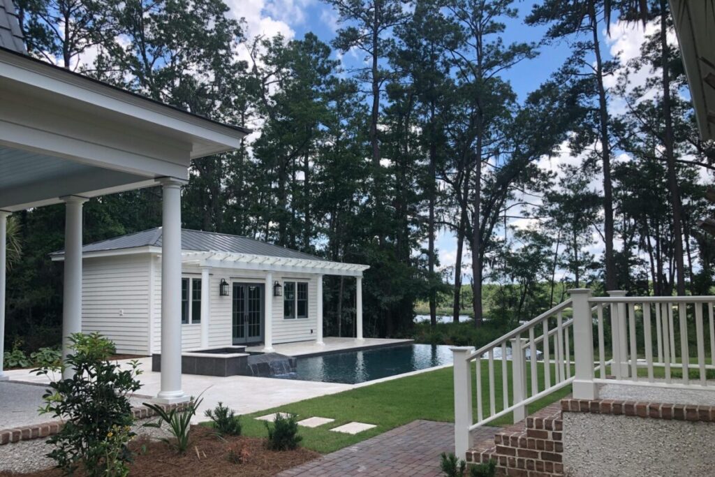 - Joanna "JoJo" Jones Luxury backyard retreat featuring a modern pool house, infinity-edge swimming pool, brick walkway, and serene wooded views creating a private resort-style outdoor living environment.