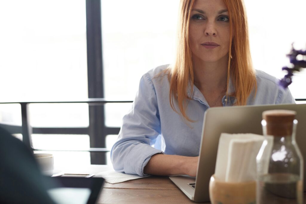 Professional woman reviewing real estate documents and property information on a laptop during an as-is home transaction consultation.