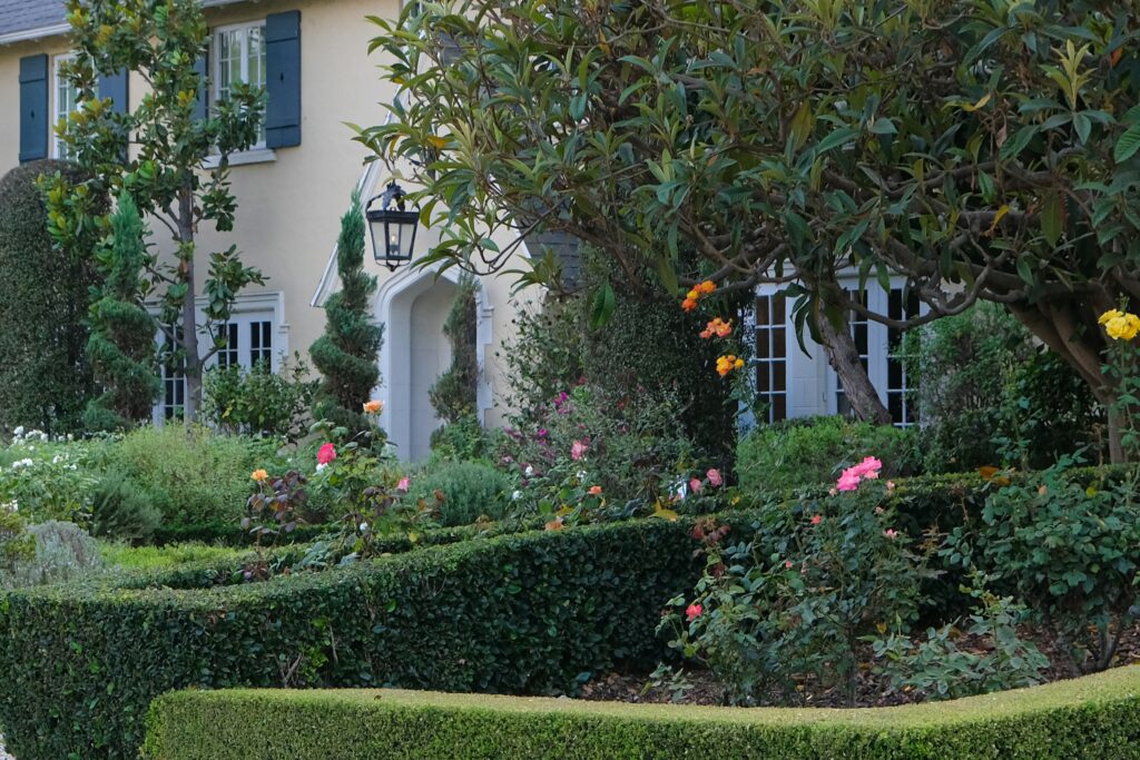 Elegant luxury home in Macon Georgia with manicured hedges, blooming rose garden, mature landscaping, and classic architectural details.