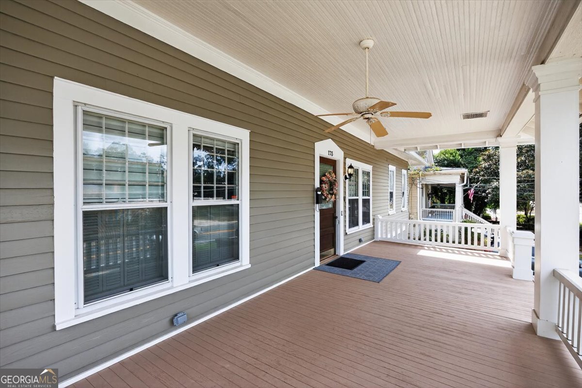 Covered front porch at 173 Pierce Avenue in Macon, GA featuring classic white columns, ceiling fan, and spacious outdoor living area.