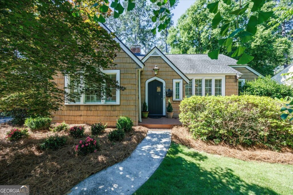 Front exterior of the historic Ingleside home at 3118 Vista Circle in Macon featuring cedar shake siding, landscaped front yard, curved walkway, mature trees, and inviting front entrance.