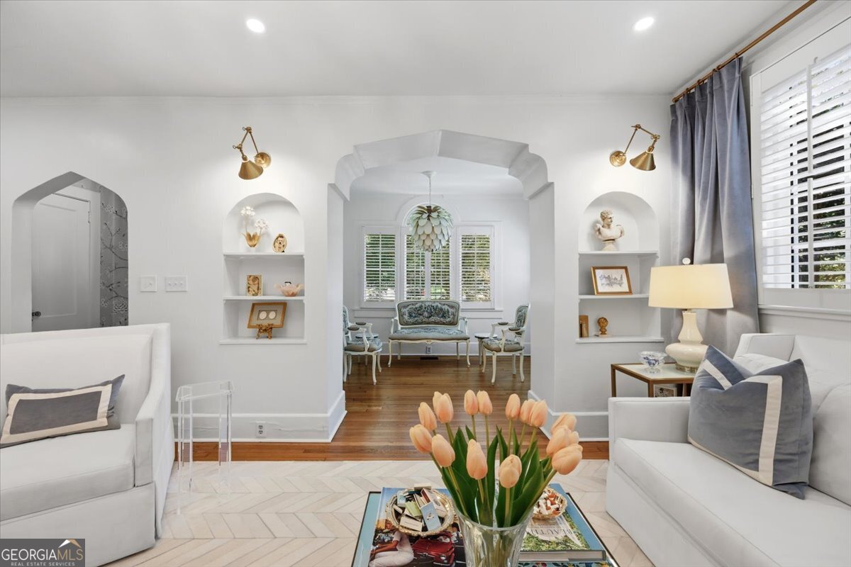 Bright living room inside the historic Ingleside home at 3118 Vista Circle featuring arched openings, built-in shelving, hardwood floors, recessed lighting, and abundant natural light.