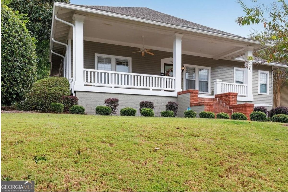 Front exterior view of 173 Pierce Avenue in Macon, Georgia featuring a charming historic cottage with a large covered front porch, white columns, landscaped yard, and classic Southern architecture.