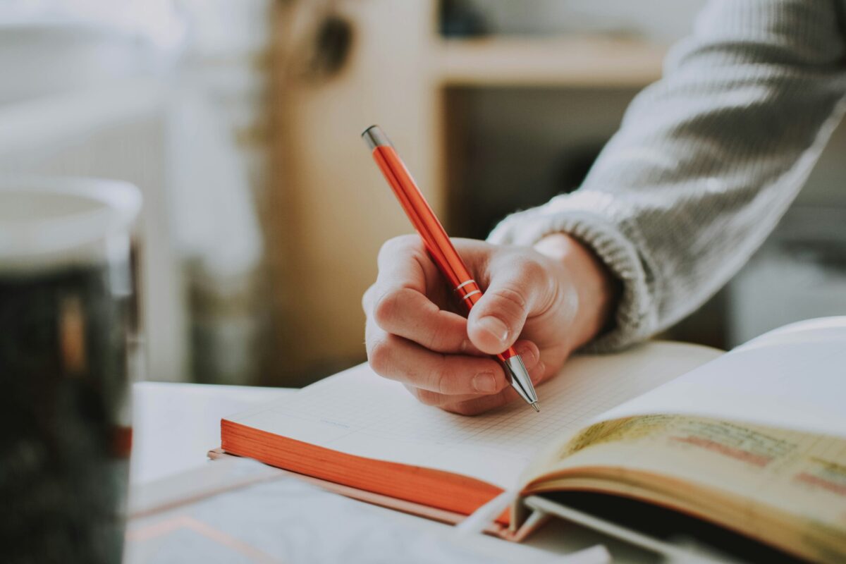Person writing a home selling checklist in a notebook while preparing a Middle Georgia home for sale before listing.