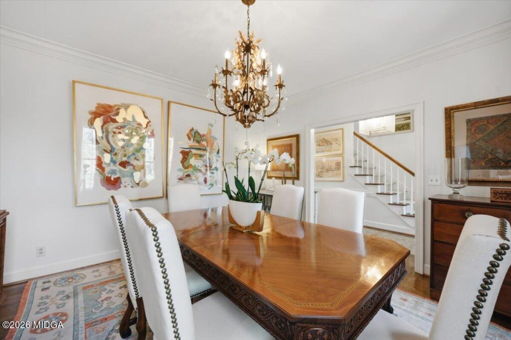 Elegant formal dining room with hardwood floors, ornate chandelier, custom artwork, and designer finishes at 102 Merion Park in Macon, GA