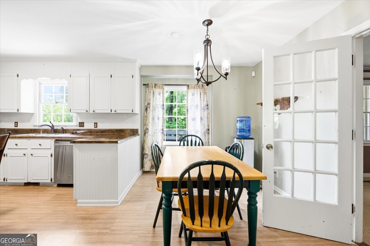 Bright eat-in kitchen at 3240 Louise Place in Macon featuring white cabinetry, breakfast area, stainless steel dishwasher, large windows, and French doors leading to the sunroom.