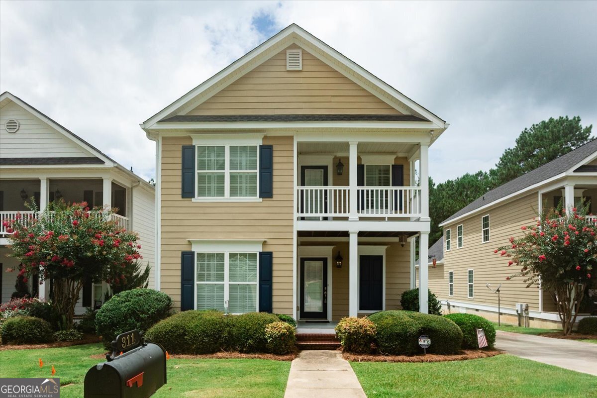 Front exterior of 311 Ivystone Drive, a two-story home for sale in Madison Subdivision, Macon, Georgia, featuring covered front porches, landscaped yard, and two-car garage.