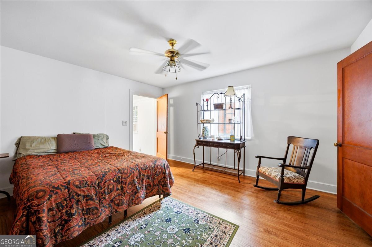 Spacious bedroom with refinished hardwood floors, ceiling fan, natural light, and classic charm in the 191 Holmes Avenue home in Vineville, Macon, GA.