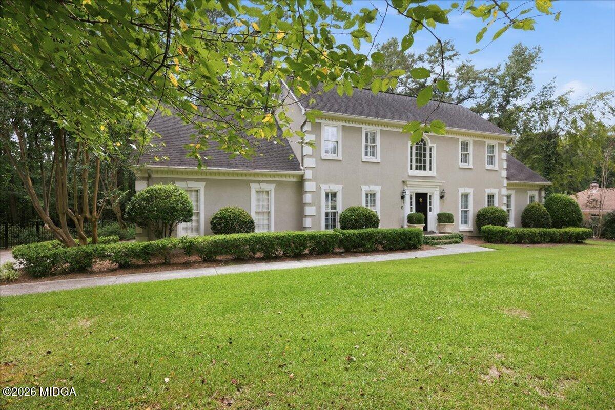 Front elevation of 118 Troon Way in St. Andrews, Macon, GA, showcasing elegant traditional architecture, manicured landscaping, mature trees, and a spacious front lawn.