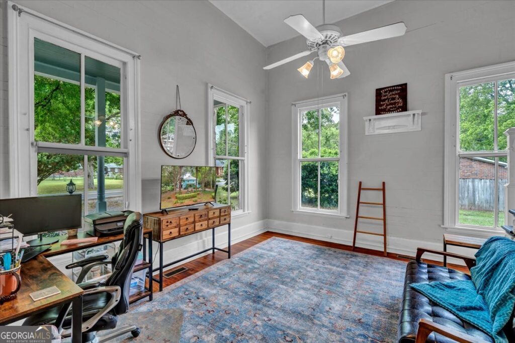 Bright historic room with tall ceilings, large windows, hardwood floors, and flexible space for a home office, sitting room, or guest living area.
