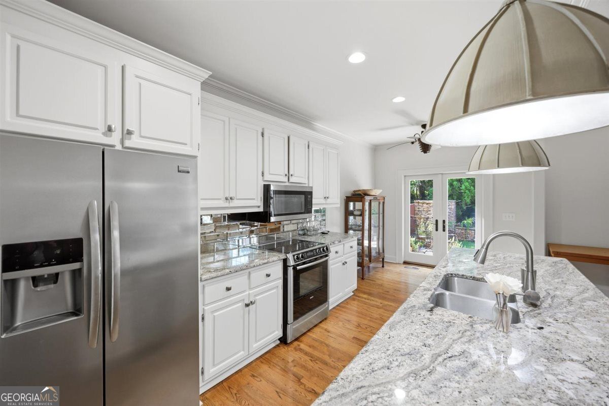 Updated Kitchen with Granite Countertops | 155 N. Wellington, North Macon - Joanna "JoJo" Jones Bright kitchen at 155 N. Wellington featuring white cabinetry, granite countertops, stainless steel appliances, hardwood floors, and French doors leading to the backyard.