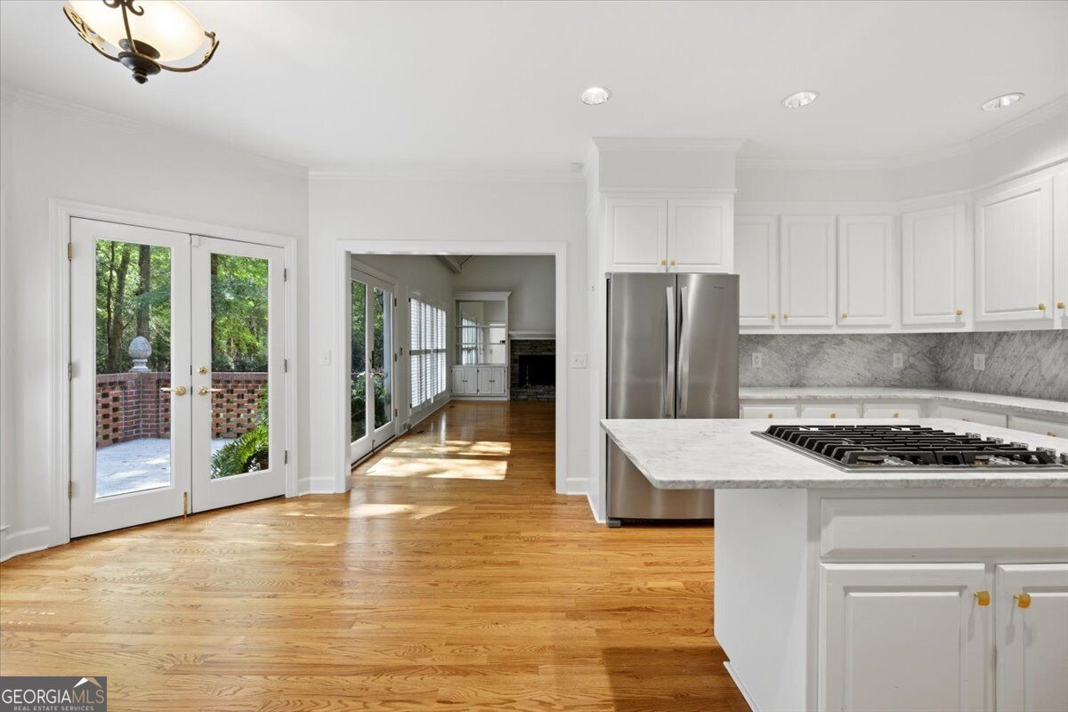 Updated kitchen at 118 Troon Way in St. Andrews featuring marble countertops, a large center island with gas cooktop, custom white cabinetry, hardwood floors, and an open-concept layout.