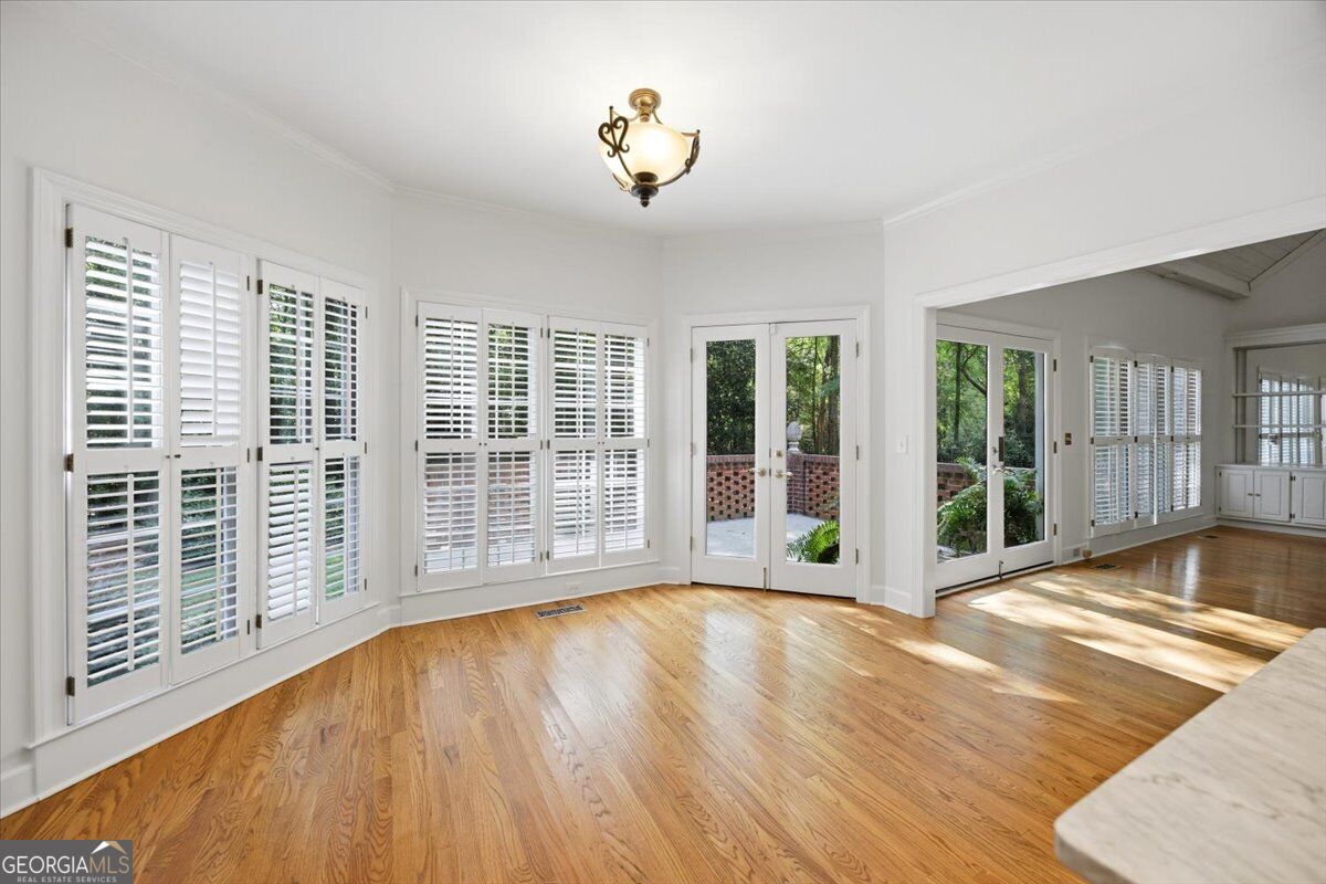 Bright living area at 118 Troon Way in St. Andrews featuring hardwood floors, plantation shutters, French doors, abundant natural light, and seamless access to the outdoor patio.