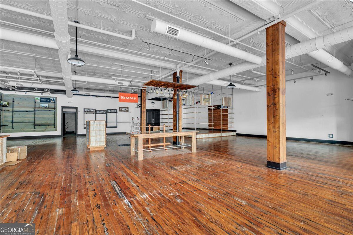 Street-level commercial interior at 565 Poplar Street in Macon, GA, featuring high ceilings, original hardwood floors, exposed ductwork, and expansive retail space.