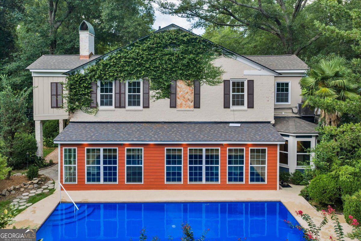 Rear exterior of 3860 Ridge Avenue in Macon, GA, featuring an in-ground swimming pool, sunroom, mature landscaping, and ivy-covered traditional architecture.
