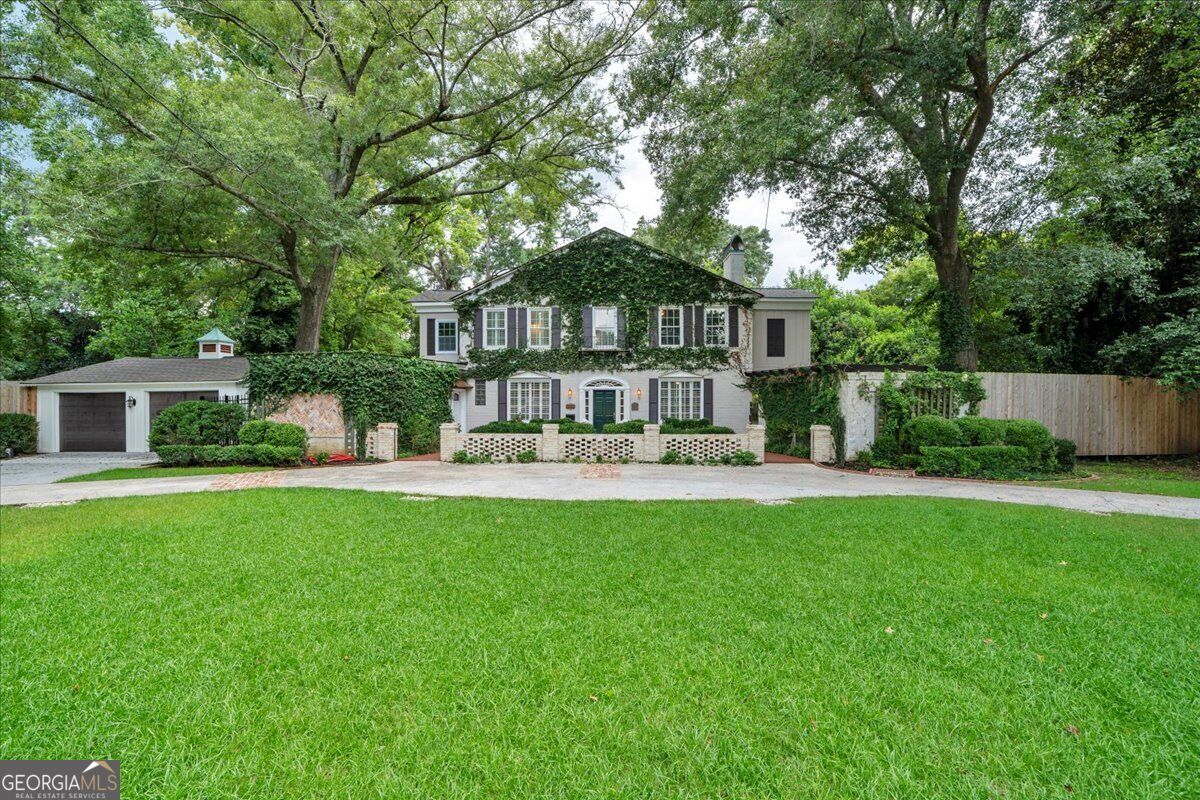 Front exterior of 3860 Ridge Avenue in Macon, GA, featuring traditional architecture, mature trees, lush landscaping, ivy-covered walls, and a spacious front lawn.