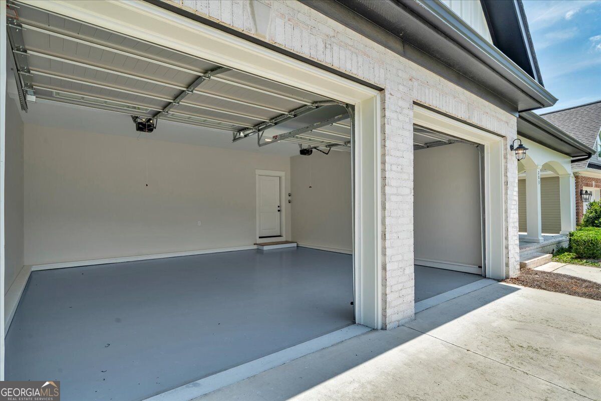 Two-car attached garage at 203 Oberon Place N in Macon, GA, featuring finished interior walls, individual garage doors, and kitchen-level access.