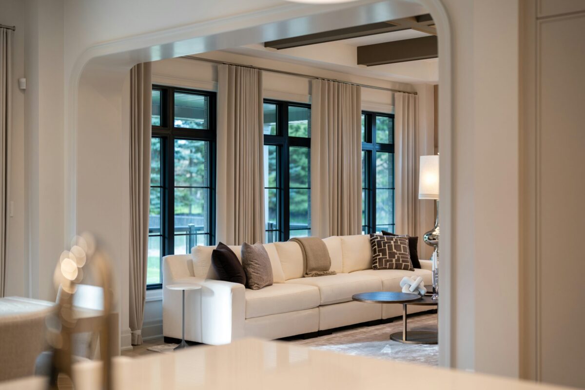 Bright, elegantly designed living room with large windows, neutral furnishings, and a spacious contemporary interior.