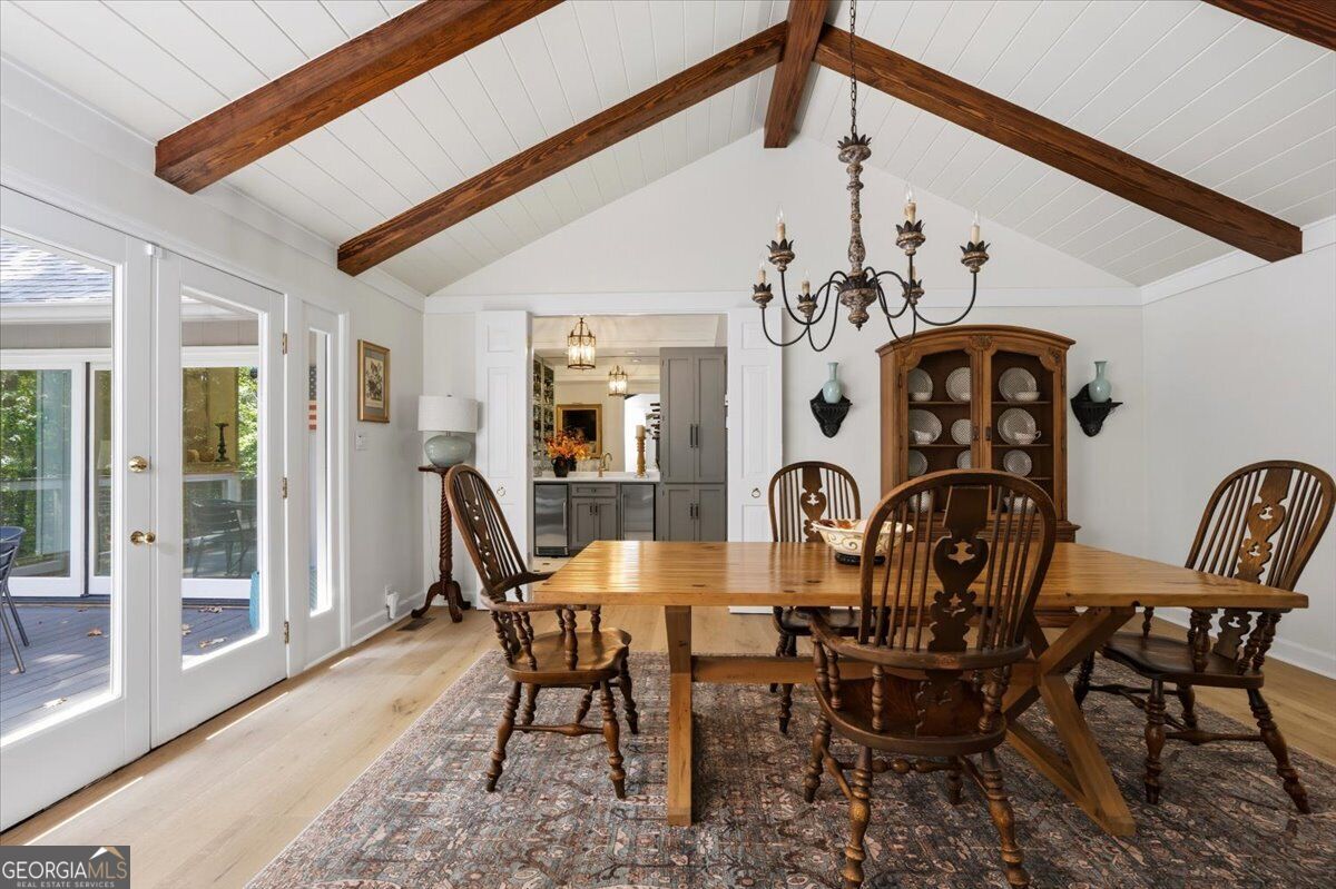Dining room with vaulted white ceiling, exposed wood beams and French doors opening to the deck at 4978 Wellington Drive