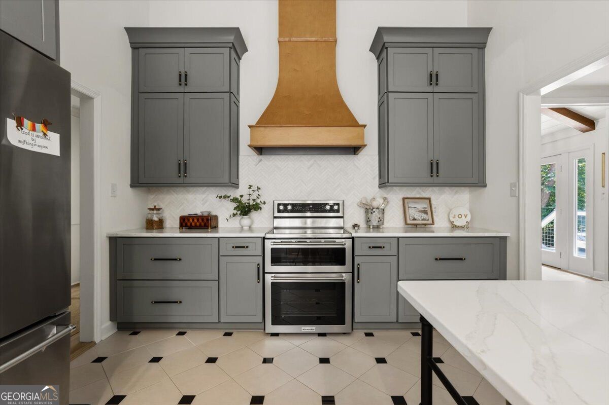 Renovated kitchen with gray cabinetry, double oven, custom wood range hood and white countertops at 4978 Wellington Drive