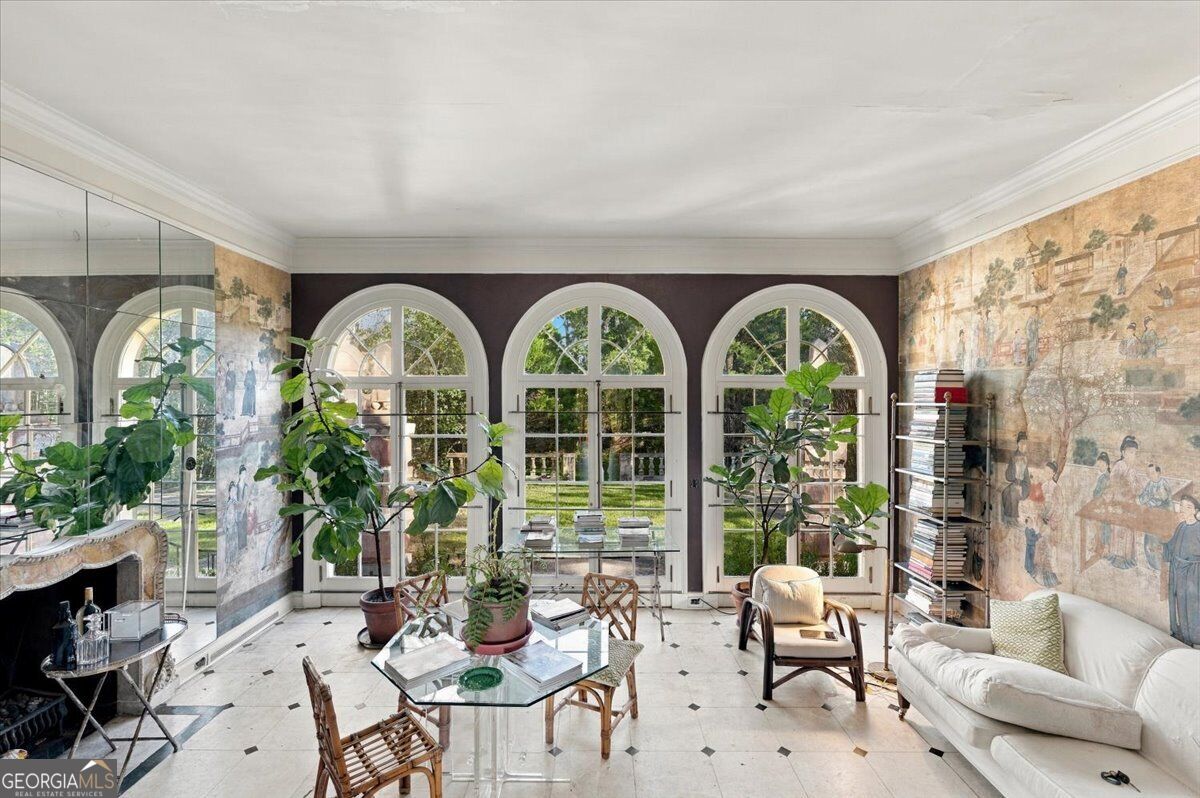 Garden room at Villa Albicini in Macon GA, featuring arched French doors, scenic wall coverings, a fireplace and patterned tile flooring.