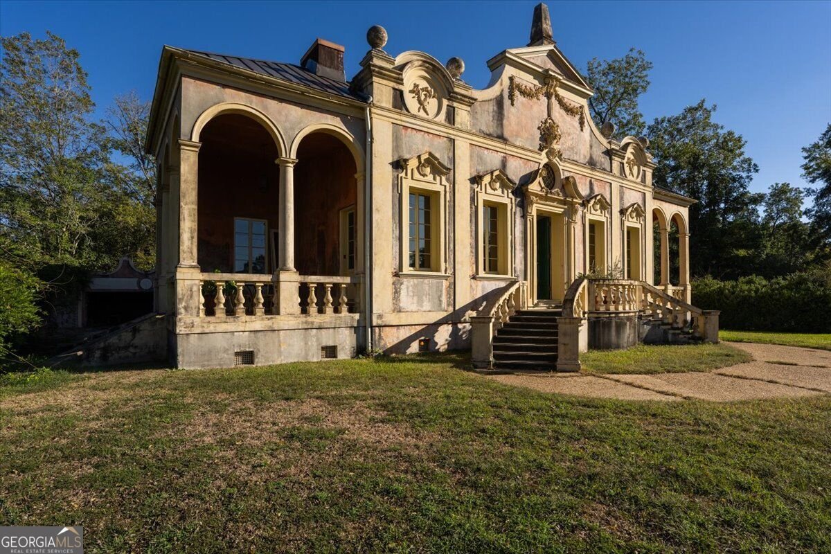 Angled exterior view of Villa Albicini in North Macon, showing arched porches, classical columns, ornate stucco details and curved entrance stairs.