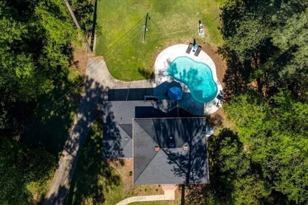 Aerial view of 3687 Overlook Drive in Macon GA, showing the home, private swimming pool, lawn and surrounding mature trees.