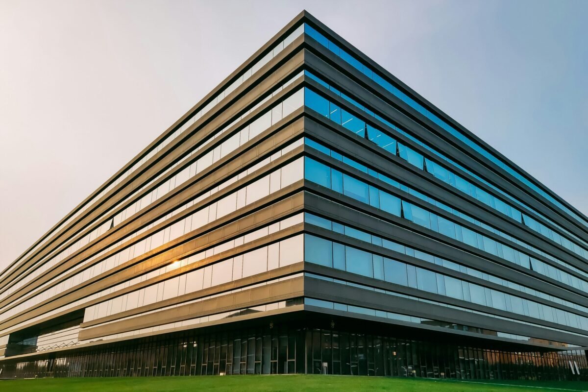 Relocating for Work in Macon GA | Home Buying and Selling Guide - Joanna "JoJo" Jones - Joanna "JoJo" Jones Modern office building with reflective glass windows and a landscaped lawn in warm evening light.